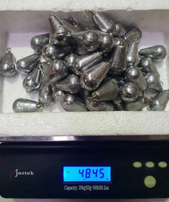 Rivernsea 58 piece pack of 3oz lead bomb fishing sinkers with swivels piled on a digital scale